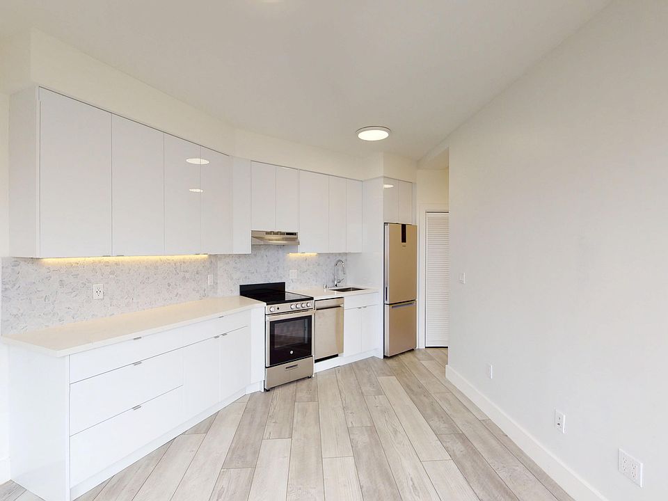 Kitchen featuring cabinets, stainless steel appliances, a marble backsplash, and wood flooring, bright and spacious design