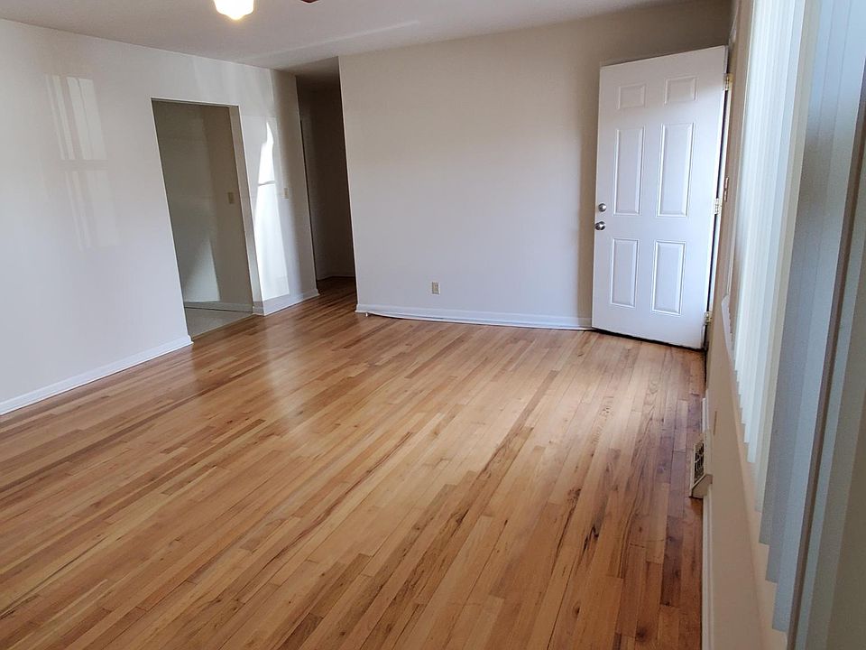 Living room looking towards bedrooms; kitchen on the left. Front door is open.