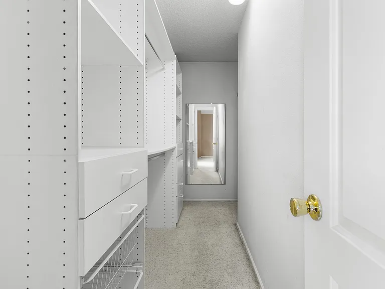 Custom walk-in closet attached to primary bedroom with built-in shelving, drawers, and exceptional storage.