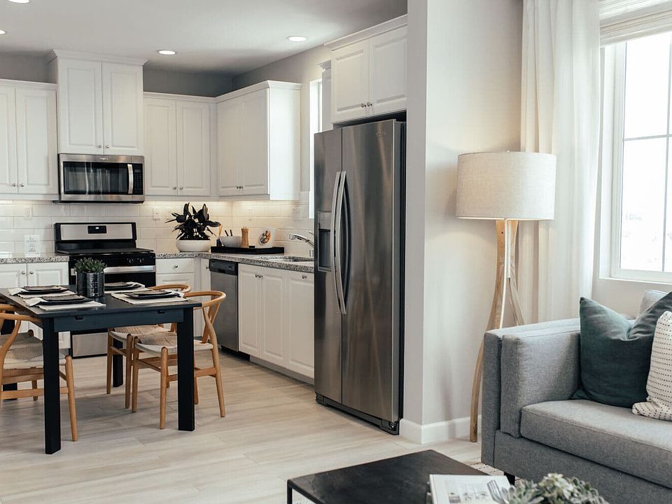 White l-shaped kitchen with table island in the Residence 1 at Citrus at Canvas Park in Ontario Ranc