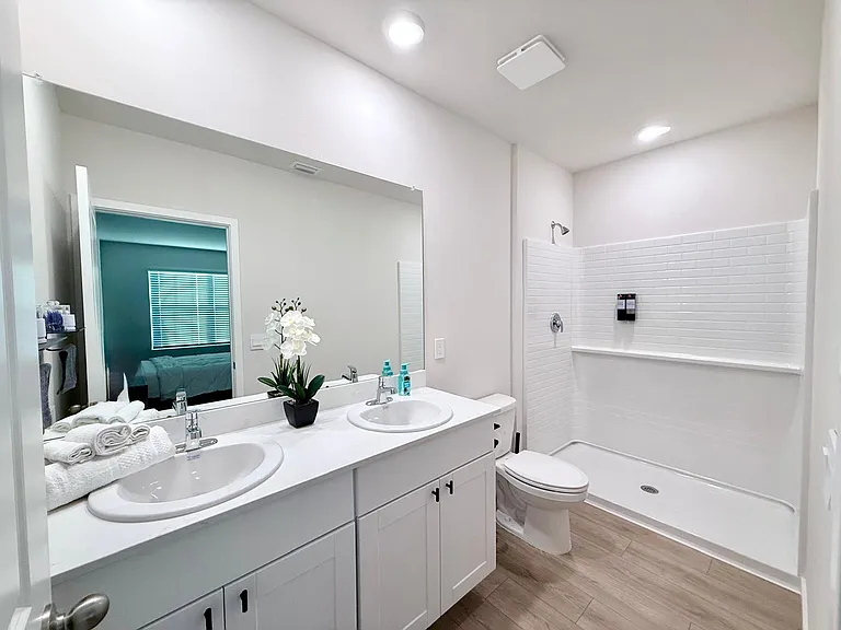 Spacious bathroom with a double-sink vanity, oversized mirror, and walk-in shower with tile surround.