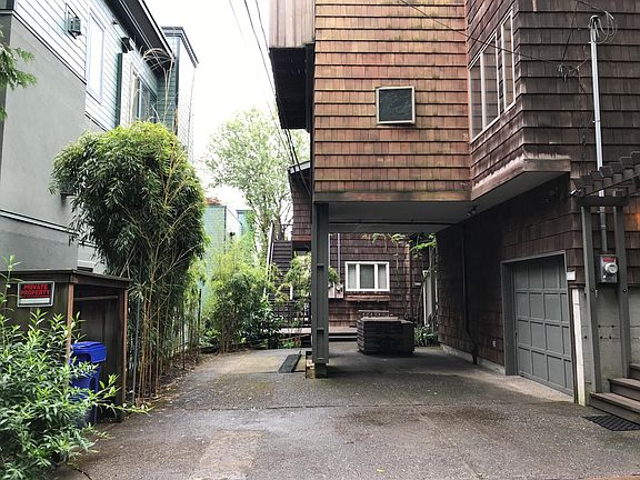 House & garage on right, carport, entrance to units in triplex beyond carport