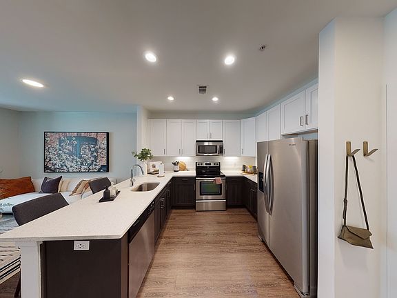 Open kitchen meticulously reimagined with two-tone cabinets, quartz counters, and stainless steel appliances