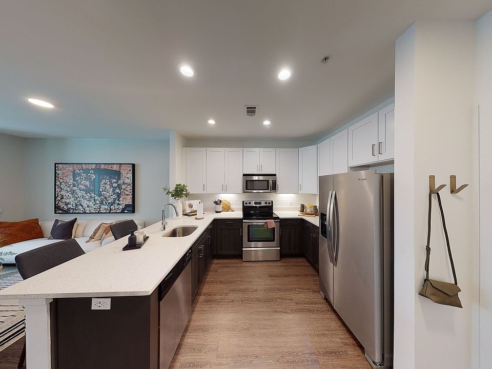 Open kitchen meticulously reimagined with two-tone cabinets, quartz counters, and stainless steel appliances