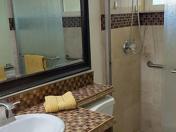 MBR private attached bathroom with renovated shower, vanity & tile.