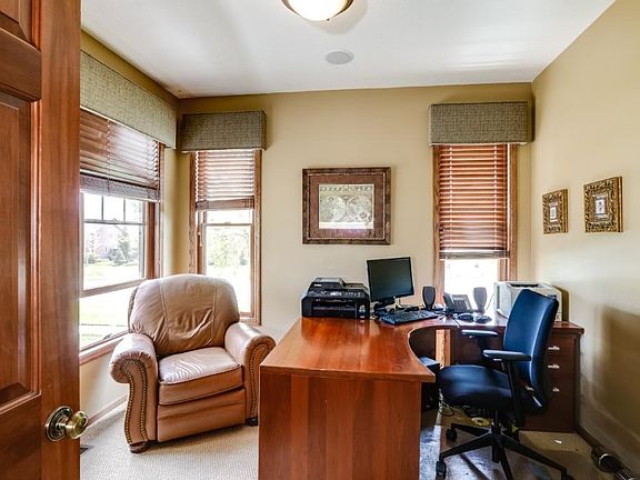 Main level flex room with patterned carpet multiple windows with custom window coverings.
