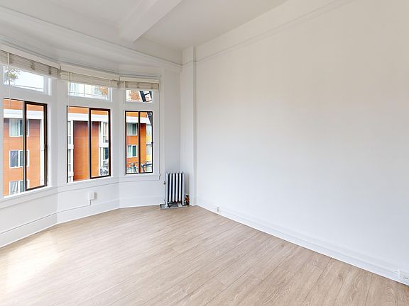 Spacious room with wood-like flooring and a large window offering natural light