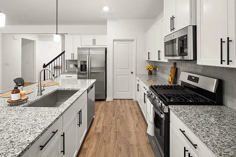 Spacious kitchen with an island, ample storage, stainless steel appliances and view into the living room.