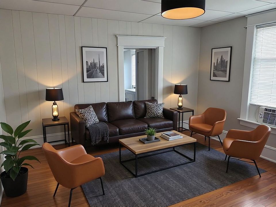 Spacious Living Room with Original Harwood Floors, Designer Lighting and New Sherwin Williams Ammonite Gray Paint Throughout.
