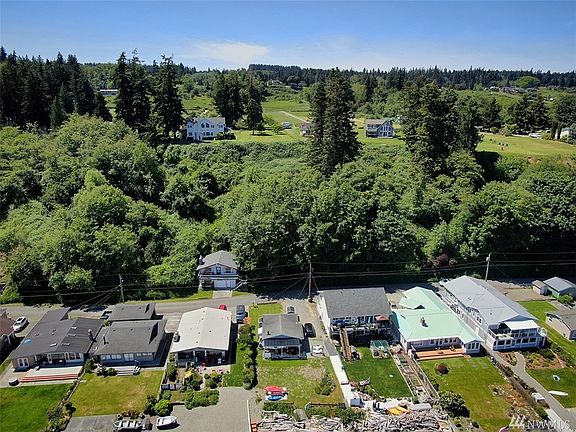 Aerial view over walking easement and looking up to acreage which is to the right of the two story white house up hill.
