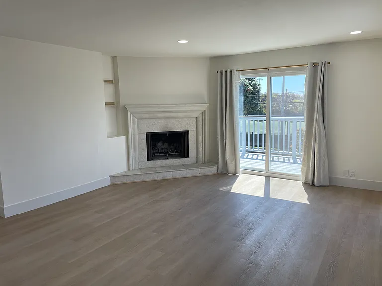 Living room featuring a fireplace, sliding glass door to a balcony, and recessed dimmable lighting