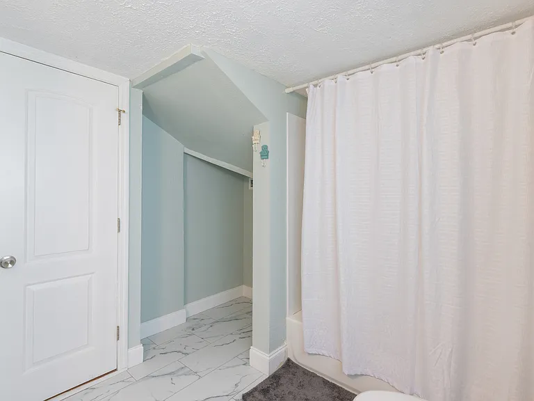Fully renovated bathroom featuring a shower/tub combo and open storage for easy access to essentials.