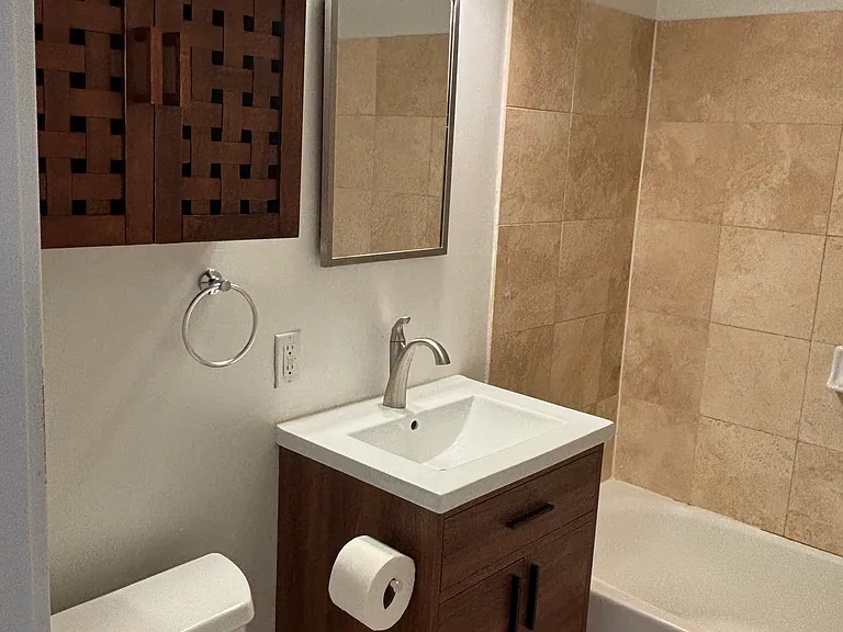 Bathroom with hidden mirror storage, vanity cabinet, and storage cabinet above toilet.