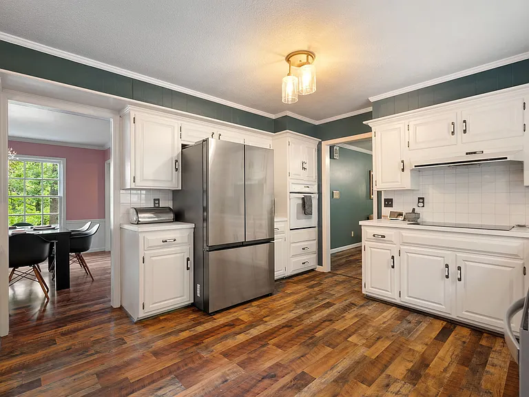 Another view of the kitchen and fridge, included in lease. The kitchen includes a new induction stovetop and stainless steel dishwasher.
