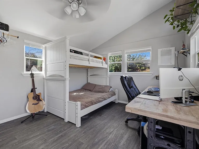 Room featuring wood-finish flooring, multiple windows, a ceiling fan, and a built-in bunk bed