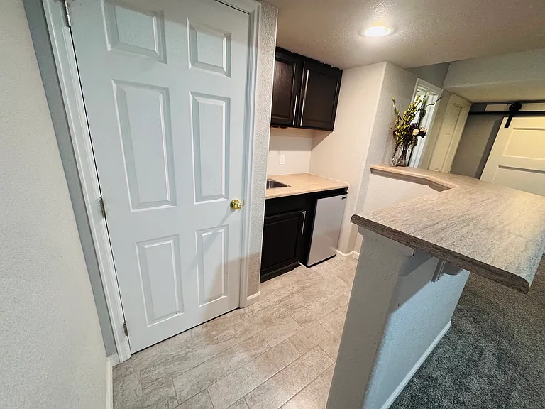 Breakfast kitchenette with a small sink, mini refrigerator, cabinet storage, and breakfast bar seating.