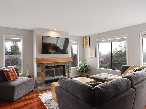 The living room features a slate wrapped wood-burning fireplace and hardwood floors. This space is perfect for cozy nights in Seattle. Large picture windows fill this area perfectly to allow just the right amount of natural light!