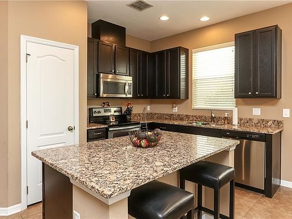 Kitchen with espresso wood cabinets and modern granite island and breakfast bar