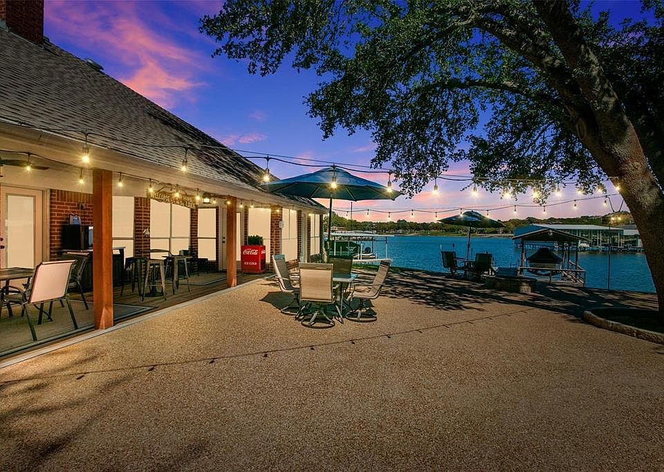 Pool at dusk with outdoor dining area, a dock, and a water view