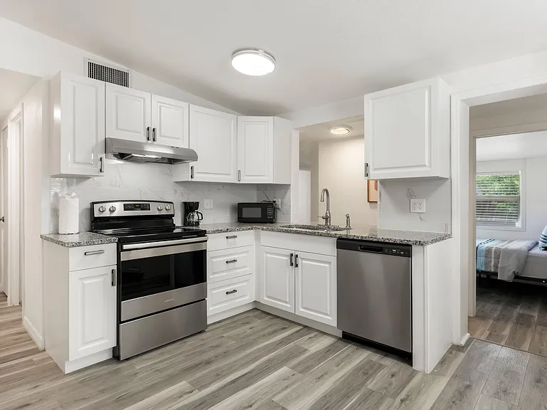 Updated U-shaped kitchen with ample cabinet storage, granite-look counters, and stainless steel range and dishwasher.