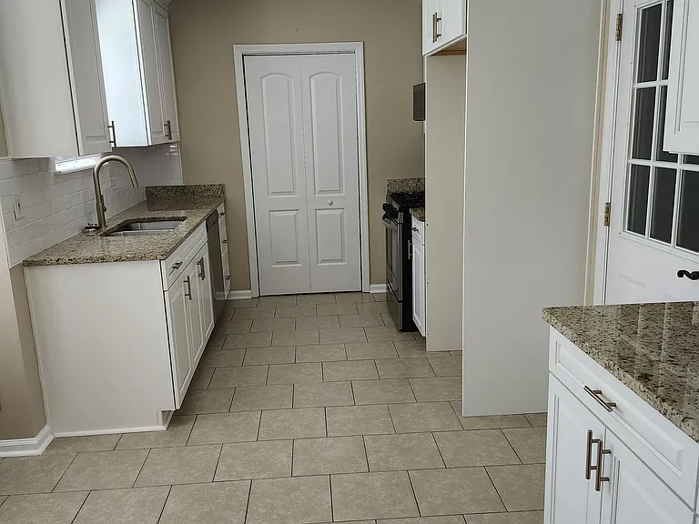 Full view of modern kitchen; beautifully designed beige tile floors; modern lights; modern cabinet hardware; granite countertops.