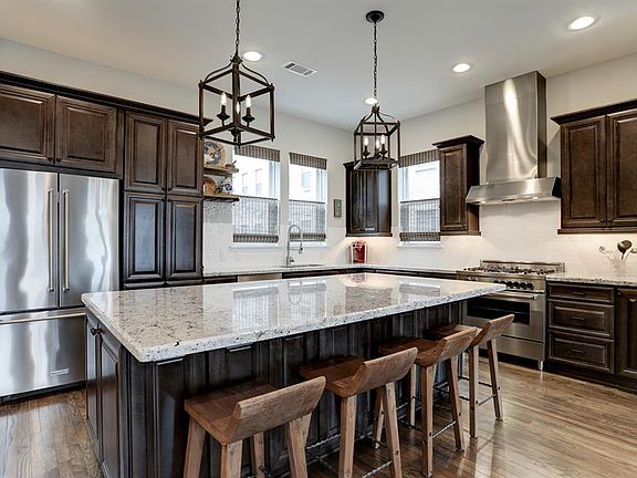 This dream kitchen has an oversized center island with tons of storage, granite counters, rich custom soft-close cabinetry, stainless appliances including an Italian Bertazonni gas range, and lots of light.