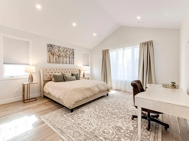 Primary Bedroom with king-size bed, blackout shades, and curtains. Large desk for workspace or vanity.