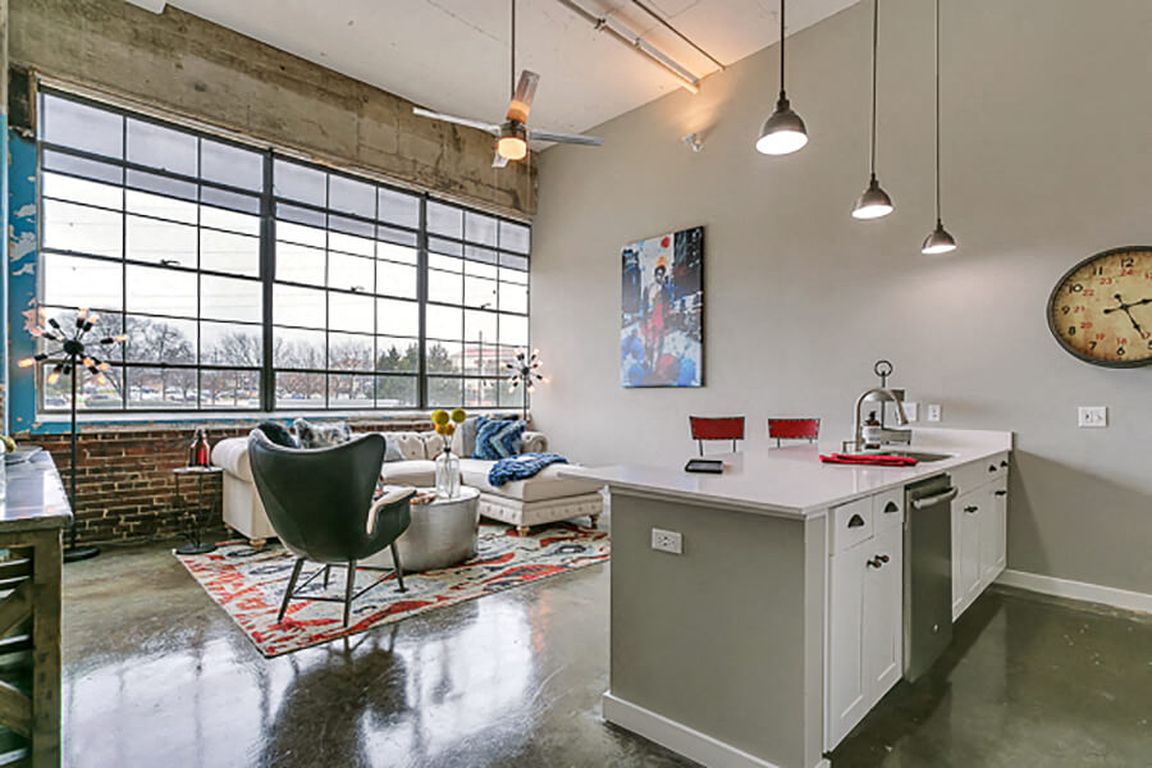 Living room with open concept kitchen, concrete floor, and beautiful white cabinets. Loft style apartment