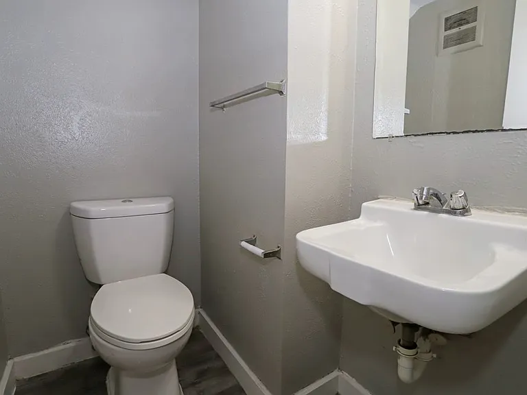 Full bathroom with large mirror, storage cabinets, and modern pedestal sink