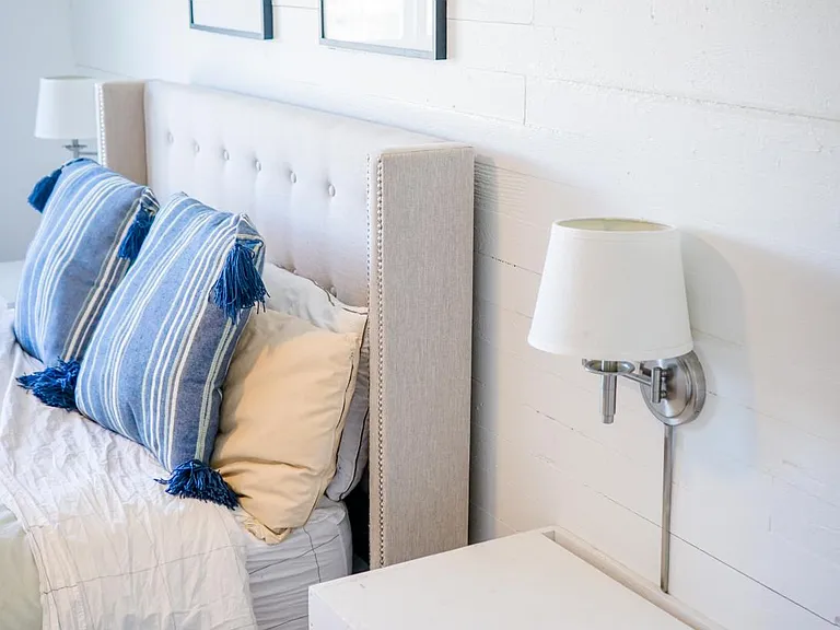 Primary bedroom has built-in, floating end tables and lights on a shiplap feature wall. Can fit a queen or king bed.