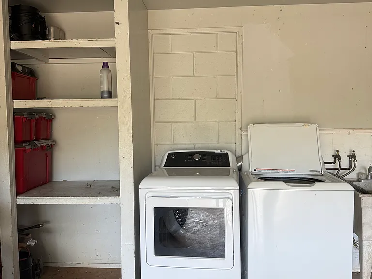Shared washer and dryer in the carport with storage cabinet for downstairs unit