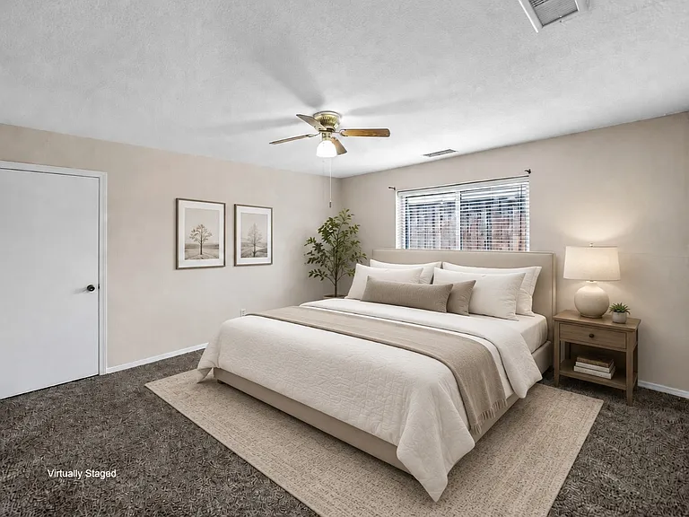 Primary suite featuring textured walls, a ceiling fan with integrated lighting, a window with horizontal blinds, and dark gray carpeting