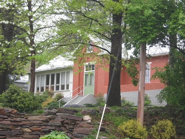 Front of house with enclosed porch on one side and patio on other.