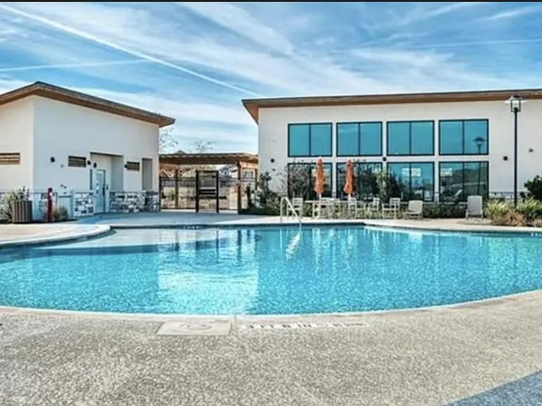 Resort-style community pool with expansive deck space, lounge seating, and nearby clubhouse facilities.