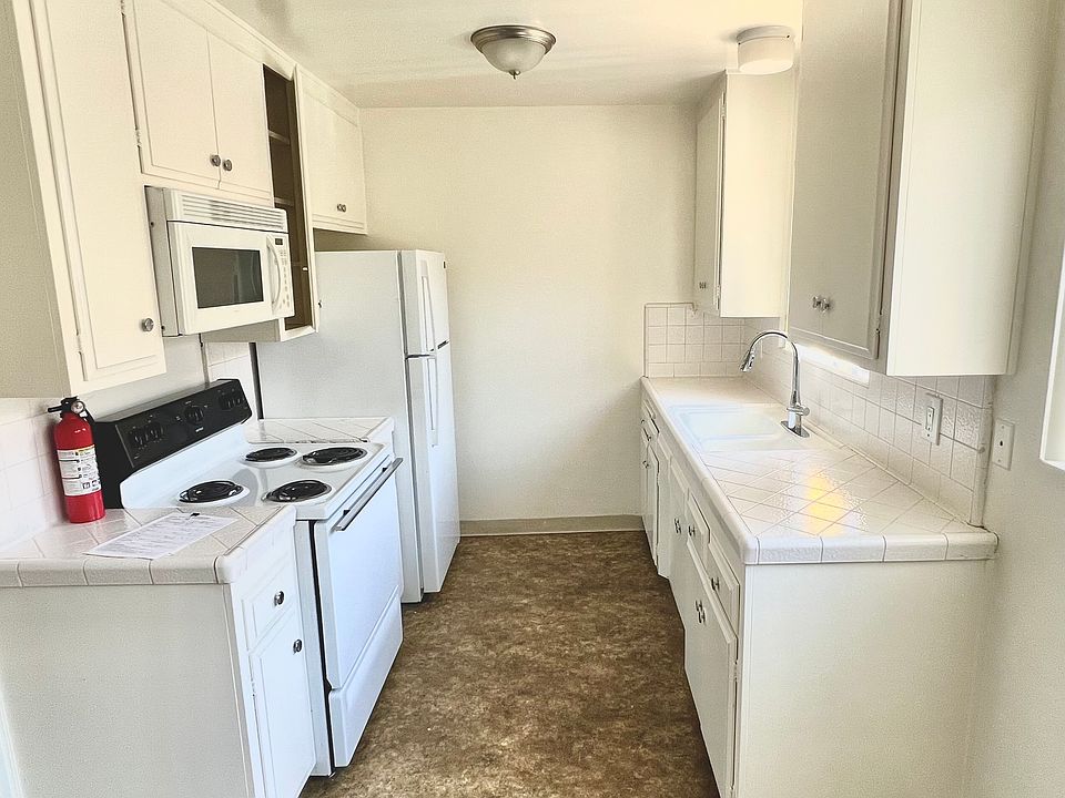 Kitchen has linoleum floors , tile countertop and new pull down faucet . Lots of cabinet space , range and built in microwave ! Window behind sink