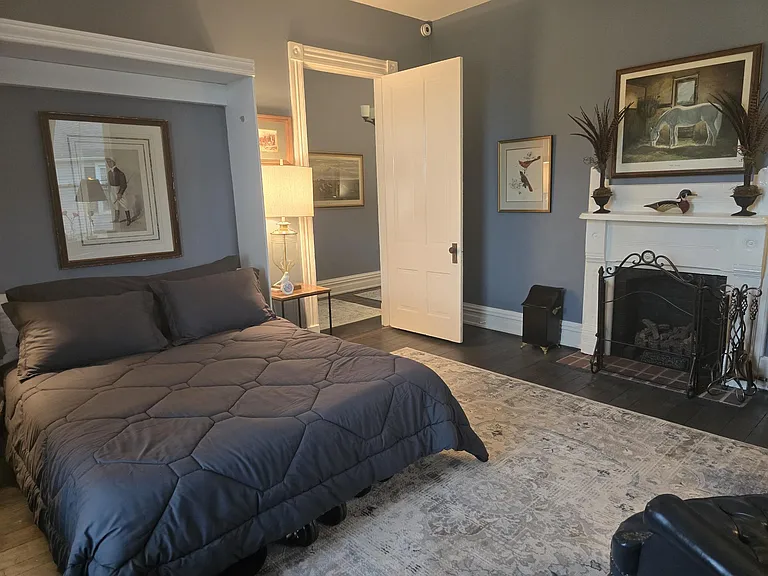 View of hallway entrance of second bedroom. Queen sized bed. Bed flips up for storage to create an office or exercise/flex room.