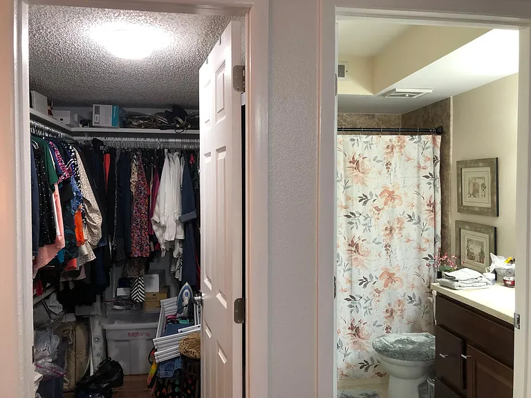 View to master bedroom with ample walk in closet with double clothes racks; step-in shower with corner seat.