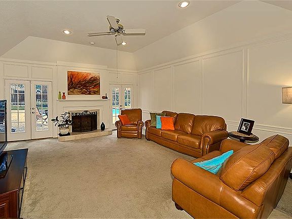Den with high ceilings, French doors leading to patio and pool area.
