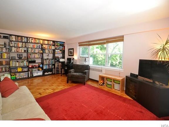 Large living room with parquet floors and two large windows featuring gorgeous tree-topped views of 
