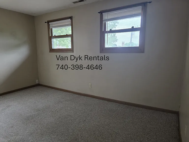 2 windows in bedroom facing street in front of house.