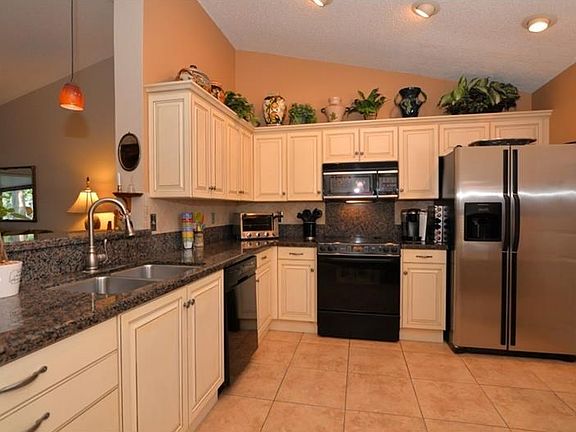 Renovated kitchen with glazed cream cabinetry, granite counters, and porcelain tile floor.