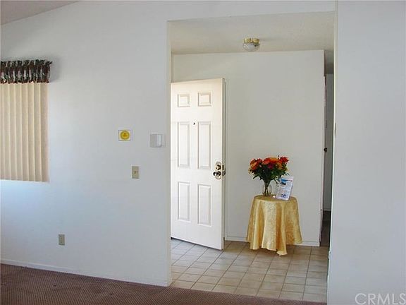TILED ENTRY WITH COAT CLOSET OPENS TO LIVING ROOM WITH DRAMATIC CEILINGS.