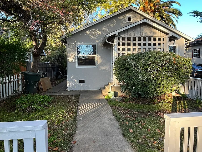 There's a cute fence on the street and a dedicated place to park one car to the right.