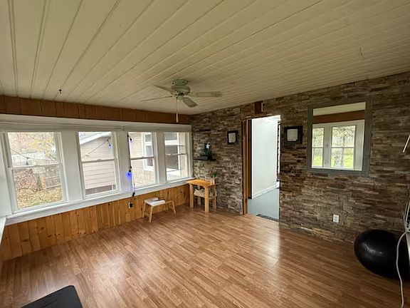 Cozy sunroom with rustic stone accent wall and warm wood finish