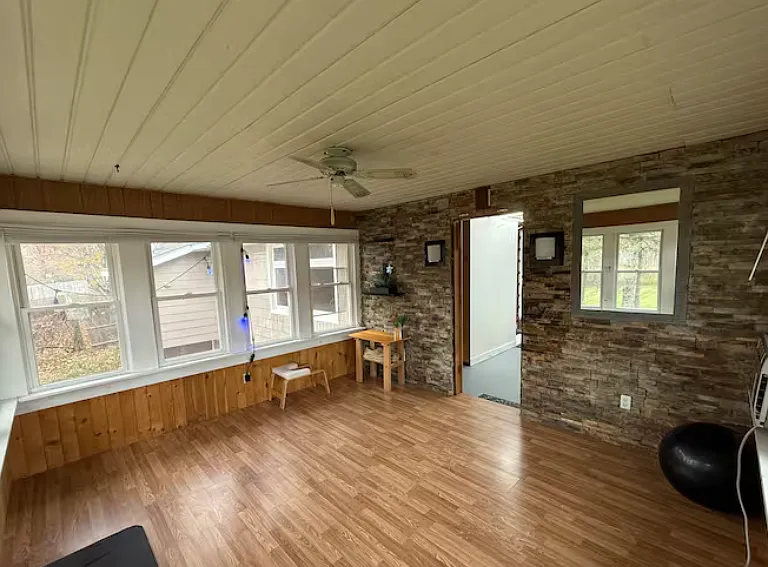 Cozy sunroom with rustic stone accent wall and warm wood finish