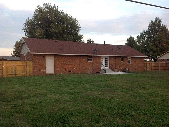 Back view of the house with French doors that opens to a large back yard with a privacy fence.
