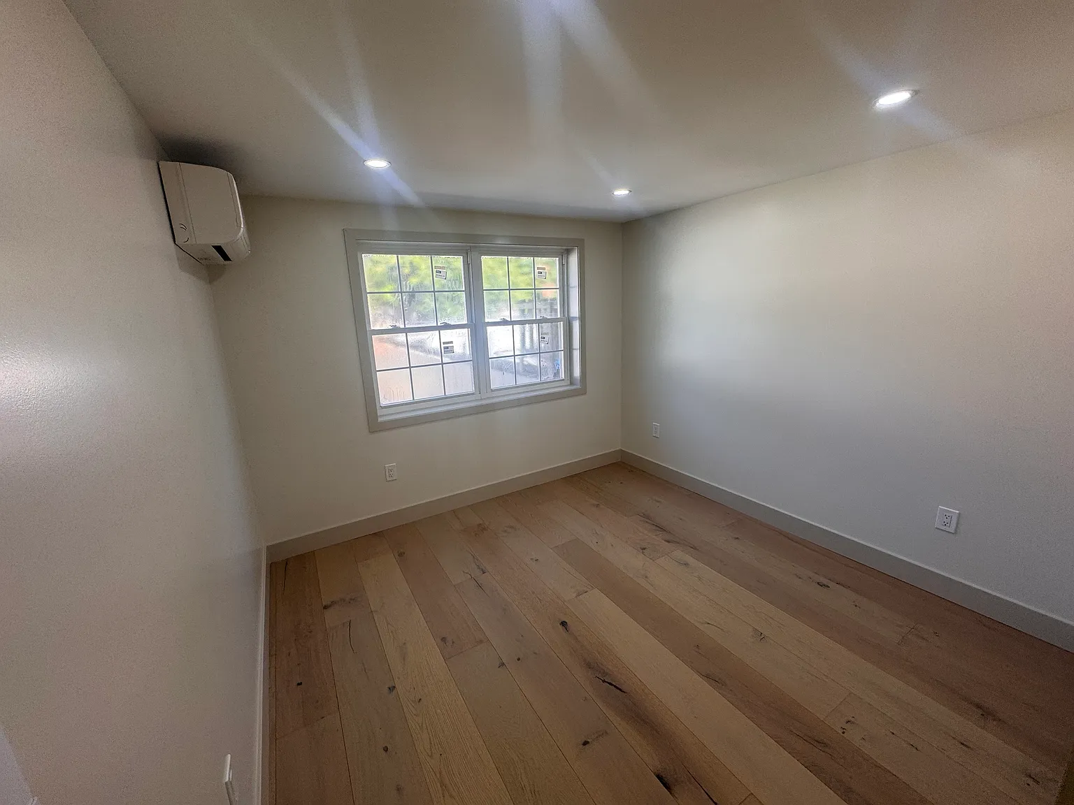 Spacious first bedroom with hardwood floors and individual climate control.