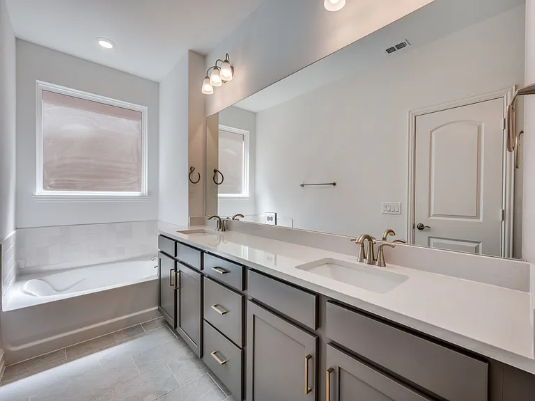 Master bath with separate vanities and a tub