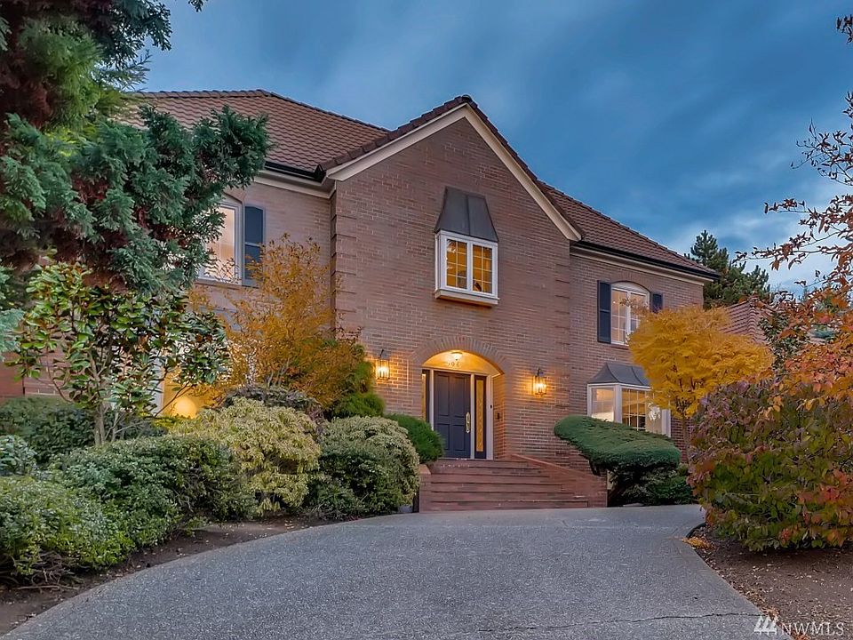 Circular drive with mature plantings on either side, plus another driveway that leads to the garage.