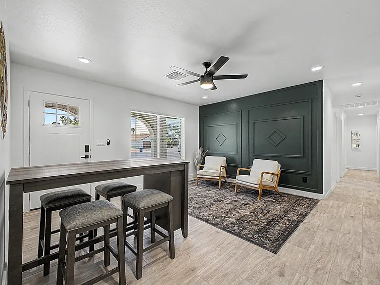 Open-concept living area with a breakfast bar, lounge seating, recessed lighting, and a ceiling fan near the entry.